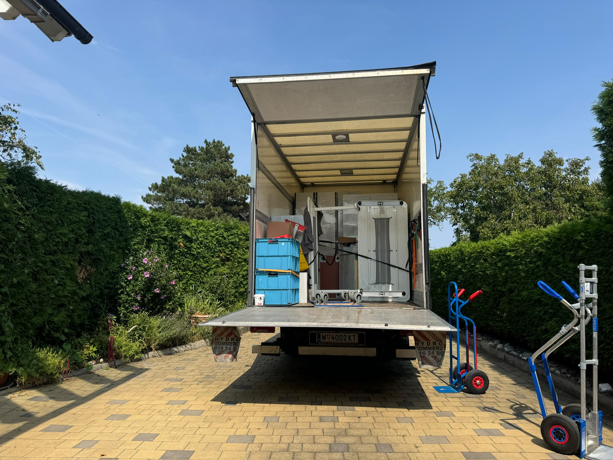 Umzugs-LKW mit Wiener Kennzeichen, offener Hebebühne und Sackkarren bei einem Umzug
